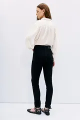 Jean slim negro de tiro medio-alto, calce al cuerpo y pierna semi-recta. Detalle de hotfix en bolsillos.