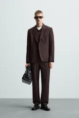 Pantalón de vestir color marrón oscuro, de corte recto, con bolsillos laterales y traseros de doble vivo. Se ajusta a la cintura con cierre de cremallera y botón.