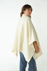 Capa con cuello, cierre frontal con botones y bolsillos delanteros. Confeccionada en lana fina sin teñir, diseñada exclusivamente por Don Baez.