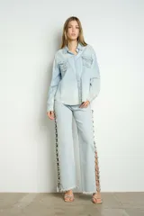 Pantalón de jean celeste con lavado claro, tiro alto, corte recto y apliques de gemas en aberturas laterales.