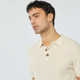 Remera polo de punto color crudo con cuello clásico, manga corta y cierre con botones de madera.