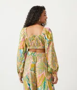Blusa cropped de viscosa con estampado tropical de follaje, escote en V con lazo, mangas largas con elástico y bajo ajustable.
