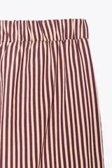 Pantalón de tiro medio con cintura elástica y bolsillos laterales ocultos en costura. Pierna ancha y estampado a rayas verticales color borgoña y blanco.