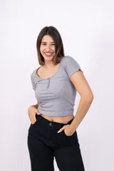 Remera corta de punto canalé color rosa, con cuello redondo y botones decorativos.