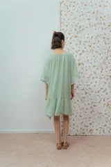 Vestido corto color beige de lino, con escote redondeado con lazo y mangas cortas amplias.