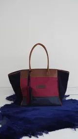 Bolso de fin de semana tipo tote bag, confeccionado en lona y gamuza, con detalles en cuero color marrón. Tiene un bolsillo interno con cierre.