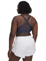 Top deportivo Under Armour con estampado floral en tonos rosa y amarillo sobre fondo negro. Cuenta con tirantes cruzados en la espalda y banda elástica con el logo de la marca en el contorno inferior.