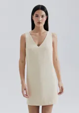 Vestido corto color crema, de corte recto y escote en V.