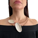 Collar corto de cuero marrón con dos óvalos de cuero color plateado.