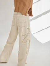 Pantalón de lino color beige con bordado artesanal de líneas onduladas en color marrón.