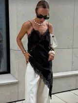 Vestido negro de satén con encaje en escote y ruedo, de corte asimétrico y breteles finos.