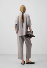 Pantalón tobillero color gris claro, de corte recto y cintura elástica. Presenta bolsillos de vivo con botón en la parte trasera.