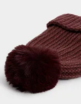 Gorro de lana tejido a crochet en color beige con detalles en blanco y pompón de piel sintética en la parte superior.