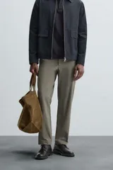 Pantalón chino de vestir negro, corte slim fit, con bolsillos laterales y traseros. Cierre frontal con cremallera y botón.