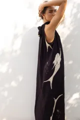 Vestido largo negro con estampado de sirenas color crema, cuello halter y corte evasé.