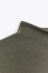 Camiseta blanca de manga larga con cuello alto y corte ajustado.