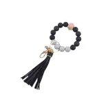 Llavero tipo pulsera con cuentas negras y grises, dije de madera y flecos de cuero sintético negro.