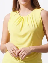 Blusa sin mangas color amarillo, con cuello redondo con frunces delanteros y abertura con botón en la espalda.