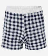 Conjunto de pijama de dos piezas compuesto por una remera de manga corta color blanco tiza con estampa de frutas en negro y un short estampado a cuadros en tonos azules y blancos.