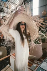 Camisa larga de manga larga, color crudo, con cuello camisero y tapeta de botones frontal con pliegues verticales.