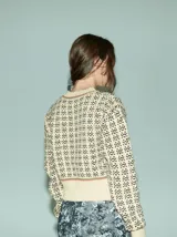 Cardigan de punto color borgoña con diseño geométrico en blanco y detalles en azul. Tiene cuello redondo, cierre frontal con botones rojos y mangas largas con puños acanalados.