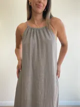 Vestido largo de lino color crudo, con escote halter fruncido y abertura lateral en la falda.