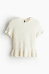 Top blanco de punto pointelle suave, corte entallado, cuello redondo ribeteado acanalado y mangas cortas con volado acanalado en puños y bajo.