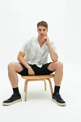 Camisa de manga corta confeccionada en lino y algodón a rayas verticales blancas y grises, con cuello americano, corte regular y logo bordado en el pecho.