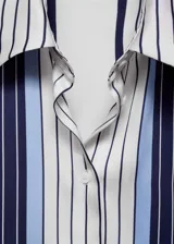 Camisa de manga larga con estampado de rayas verticales azules y blancas, confeccionada en tejido fluido con acabado satinado. Presenta cuello camisero, cierre frontal con botones y puños abotonados. Diseño recto y calce regular.