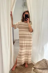 Vestido largo tejido artesanalmente a rayas horizontales en tonos beige y marrón claro, con mangas cortas y corte recto con aberturas laterales.