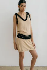 Minifalda color beige con detalle de volados negros en escote, cintura y sisas.