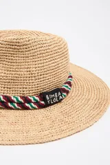 Sombrero de paja con ala ancha y cinta decorativa trenzada en la base de la copa, en colores verde, rojo y blanco.