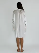 Vestido corto color ocre, con cuello mao, mangas largas abullonadas con detalle de encaje y corte evasé.