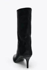 Bota de cuero sintético negro con efecto arrugado, terminación en punta y tacón fino.