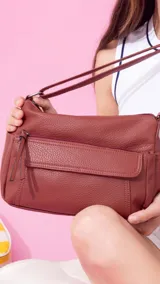 Bandolera de cuero sintético color marrón, con dos bolsillos frontales, uno con tapa y cierre. Interior espacioso con bolsillos.