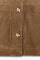 Cazadora marrón de piel con cuello solapa, manga larga, bolsillos de parche delanteros y cierre frontal con botones.