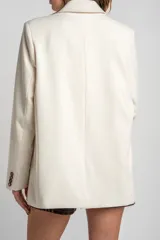 Blazer color crema, de corte oversize, con solapas de muesca, cierre con doble botón y bolsillos laterales con solapa.