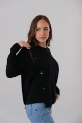 Sweater negro de punto con cuello redondo y corte recto. Presenta detalle de botones grandes en el hombro.