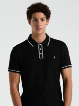 Polo negra de piqué con vivos blancos en cuello y mangas, calce slim fit y logo bordado en el pecho.
