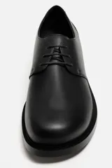 Zapato de vestir de cuero negro, tipo derby con cordones, punta redondeada y suela con ligero tacón.