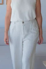 Pantalón de vestir ancho de tiro alto, color crudo con finas rayas verticales negras. Presenta pinzas frontales y cierre con botón visible.
