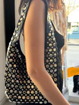 Cartera negra tipo hobo con tachas plateadas.