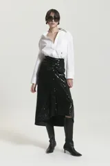 Pollera midi negra de lentejuelas con frunce en el centro delantero. El ruedo es asimétrico, más largo en los laterales que en el centro delantero, y recto en la espalda.