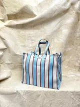 Bolso grande de plástico reciclado con diseño rayado en azul y blanco, cuenta con cierre y bolsillo interior.