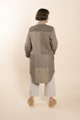 Camisa larga color beige con cuello mao, manga larga con tajo y botón. Diseño con bloques de tela con textura.