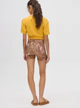 Short biker ajustado de lycra con estampado abstracto y difuminado en tonos verdes, naranjas, azules y rosados. Presenta costuras visibles en contraste y un pequeño logo bordado en la pierna derecha.