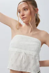 Top strapless de encaje bordado, color blanco, con detalle de cinta ajustable en la parte frontal.