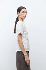 Blusa de manga corta color crudo, con cuello redondo y diseño de encaje bordado floral.