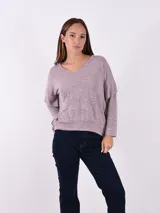 Buzo de tejido melange gris claro, con cuello en V y manga larga. El calce es holgado y el ruedo ajustado con elástico.