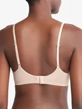 Corpiño Calvin Klein color piel, ligeramente forrado, sin aros, con breteles finos con logo de la marca y escote en V.